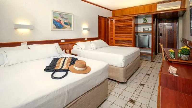 Duas camas de casal arrumadas no Apartamento Classic, com armário de madeira ao fundo