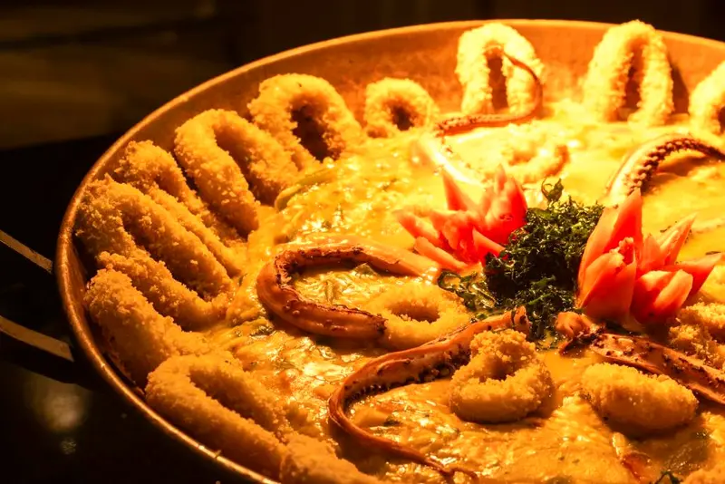 Travessa de arroz com lulas e frutos do mar decorada com legumes