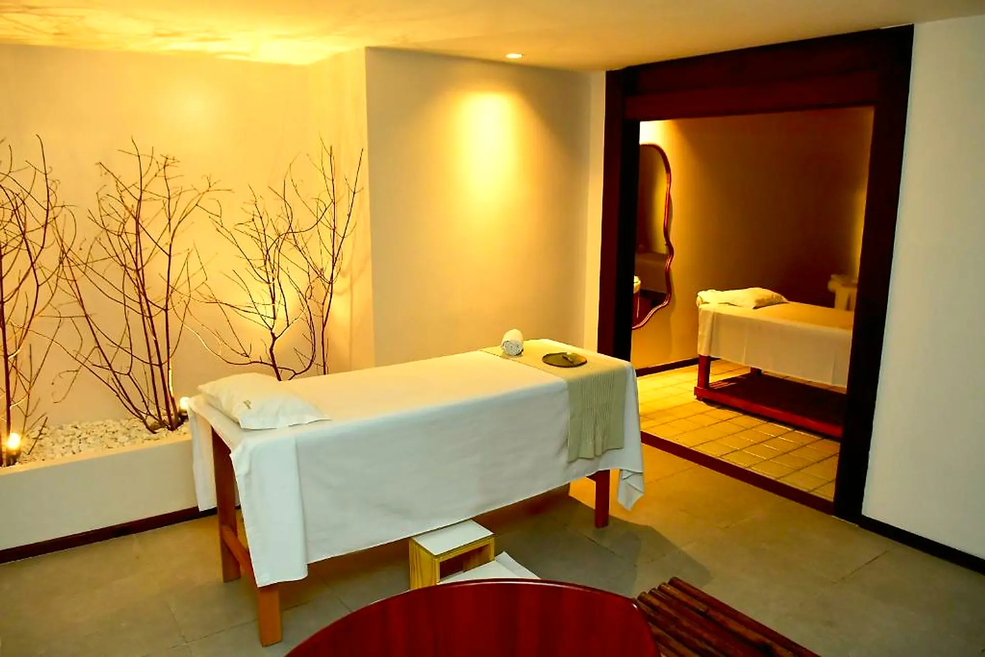 Sala de massagem do spa com maca, galhos decorativos e iluminação suave