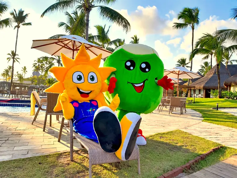 Dois mascotes da Turma do Summy, o sol e o coco, sentados perto da piscina